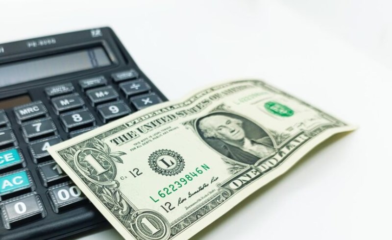 달러 지폐와 계산기 위에 놓인 안경